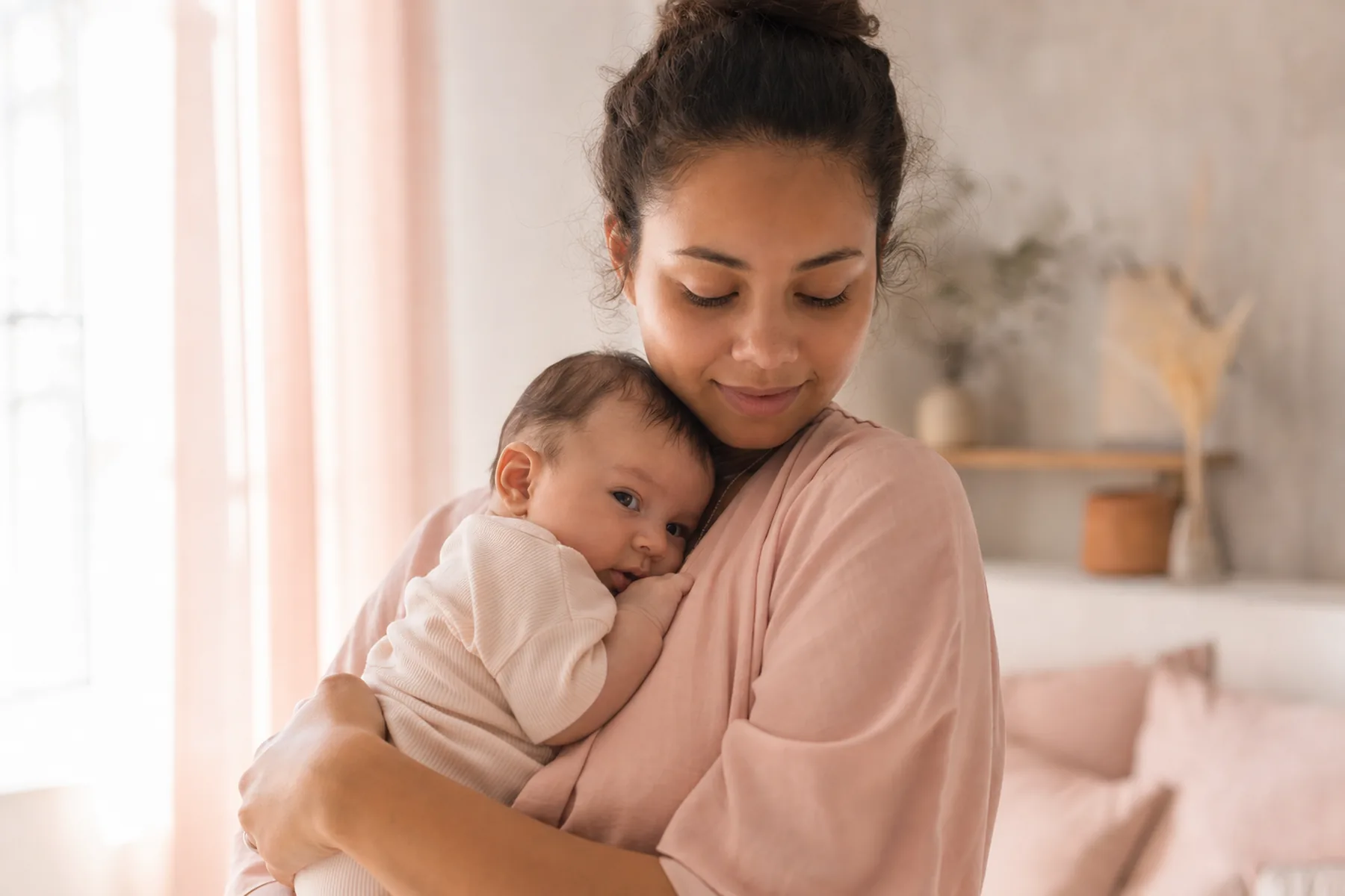A mother holding her infant close in soft morning light